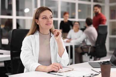 Photo of Team of employees working together in office. Happy woman at table indoors