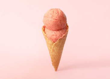 Photo of Delicious ice cream in waffle cone on pink background