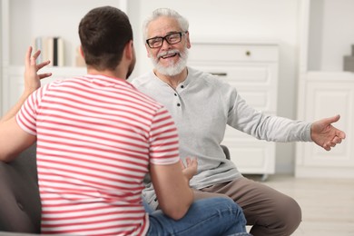 Photo of Happy son and his dad talking at home