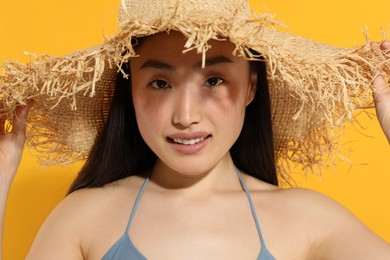 Photo of Beautiful young woman in straw hat on orange background