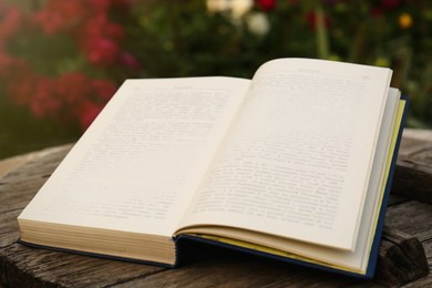 Photo of Open book on wooden table in garden