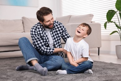 Photo of Happy dad and son having fun on carpet at home
