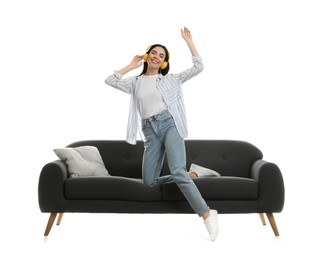 Photo of Young woman listening to music on comfortable grey sofa against white background