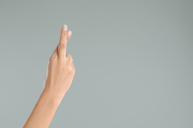 Photo of Woman with crossed fingers and space for text on grey background, closeup. Superstition concept