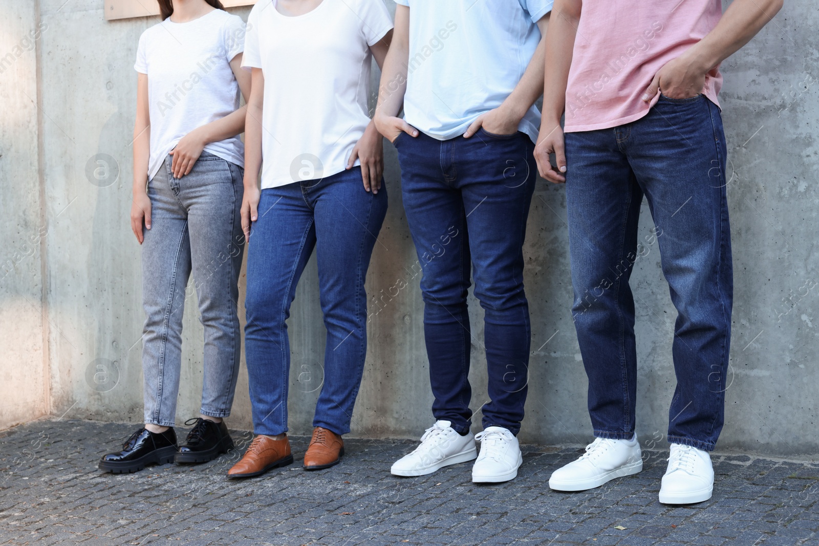 Group of people in stylish jeans near grey wall outdoors, closeup Photo of Group of people in stylish jeans near grey wall outdoors, closeup
