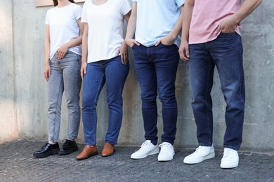 Photo of Group of people in stylish jeans near grey wall outdoors, closeup