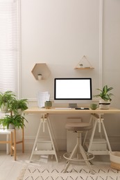 Photo of Comfortable workplace with modern computer and houseplants in room. Interior design