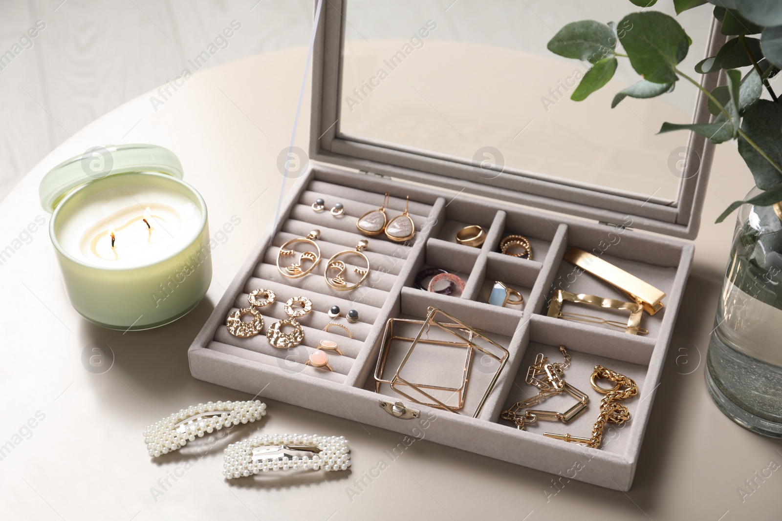 Photo of Elegant jewelry box with beautiful bijouterie and candle on beige table