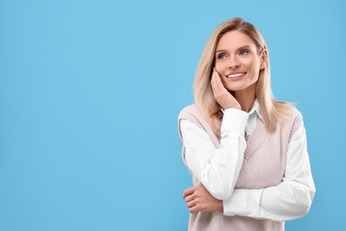 Photo of Portrait of smiling middle aged woman on light blue background. Space for text
