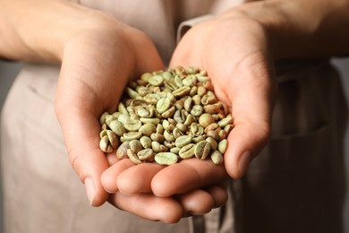 Photo of Woman holding pile of green coffee beans, closeup