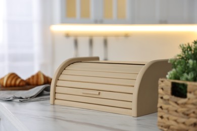 Photo of Wooden bread box on white marble table in kitchen