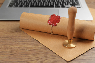 Photo of Notary's public pen and sealed document near laptop on wooden table