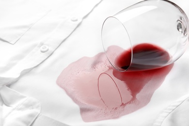 Photo of Overturned glass and spilled exquisite red wine on white shirt. Space for text