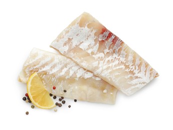 Photo of Fresh raw cod fillets with peppercorns and lemon isolated on white, top view