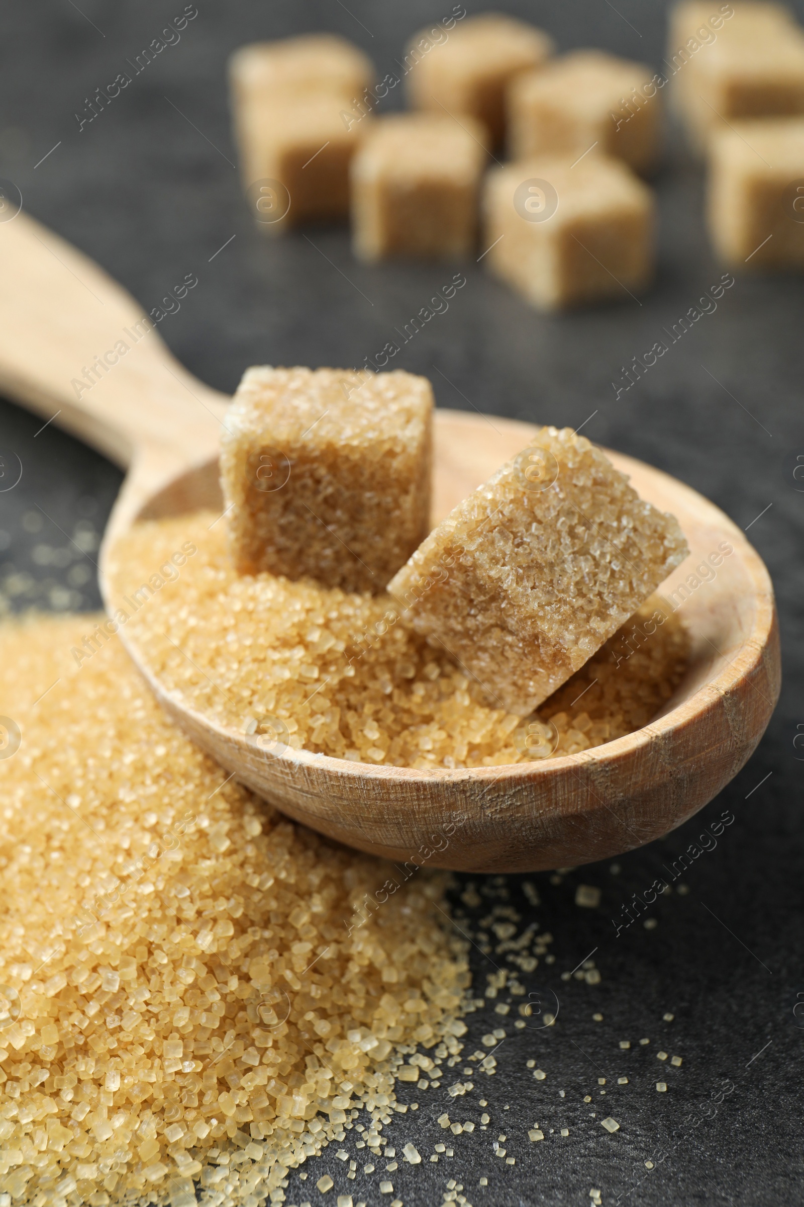 Spoon with brown sugar cubes on grey table, closeup Photo of Spoon with brown sugar cubes on grey table, closeup