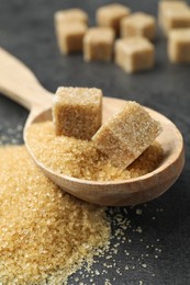 Photo of Spoon with brown sugar cubes on grey table, closeup