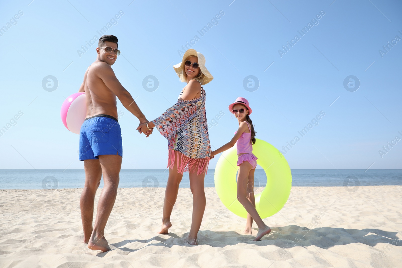 Photo of Happy family with inflatable toys at beach on sunny summer day