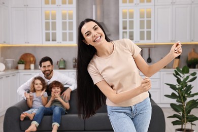 Photo of Happy family having fun at home. Mother dancing while her relatives resting on sofa