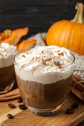 Photo of Glass with tasty pumpkin spice latte on wooden table
