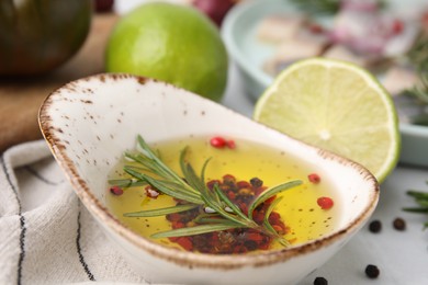 Tasty fish marinade with rosemary and products on light table, closeup