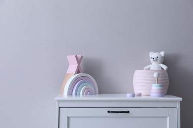 Photo of Child's toys on chest of drawers near light grey wall indoors
