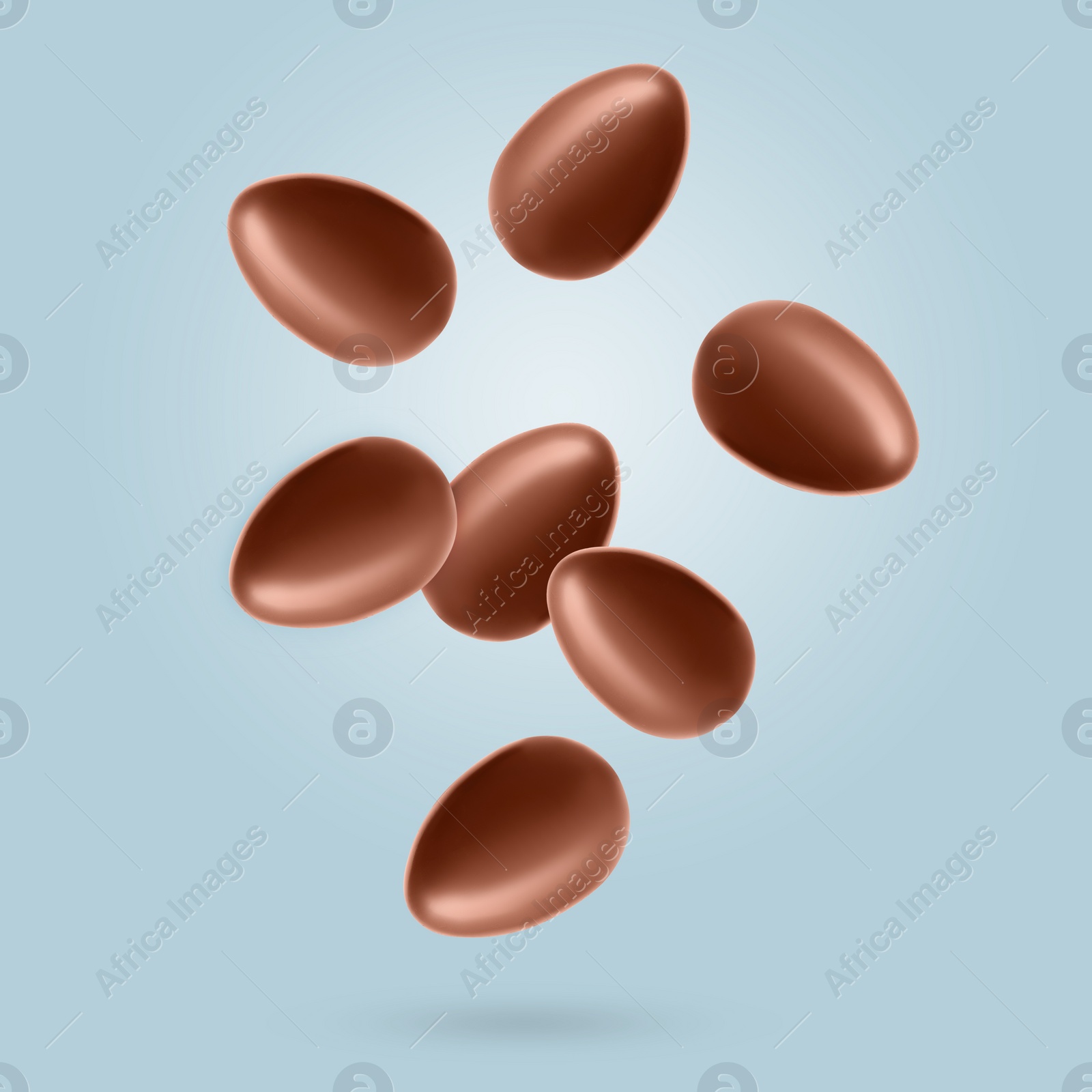 Image of Many chocolate eggs falling on dusty light blue background