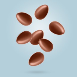 Image of Many chocolate eggs falling on dusty light blue background