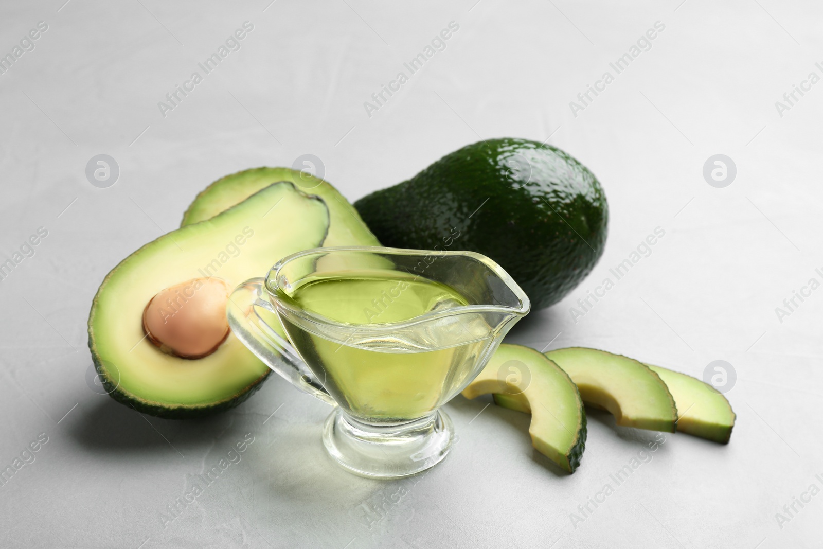 Photo of Composition with natural oil and avocados on grey stone background