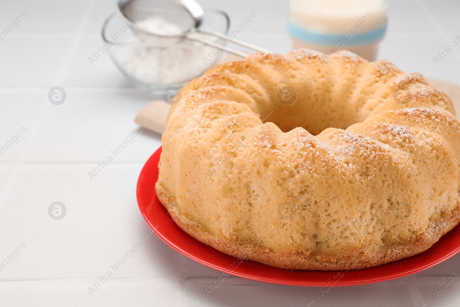 Photo of Delicious freshly baked sponge cake on white tiled table, closeup. Space for text