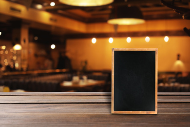 Blank small blackboard on wooden table in cafe, mockup for menu design 