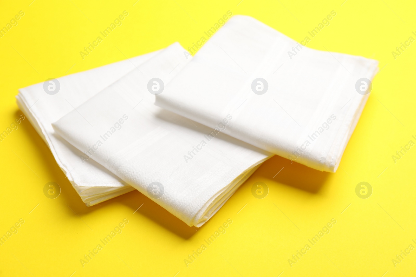 Photo of New stylish white handkerchiefs on yellow background