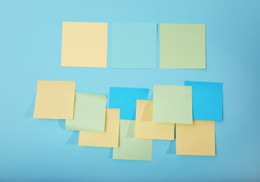 Colorful sticky notes on light blue background, flat lay