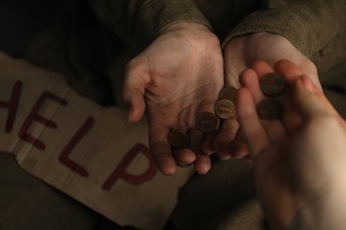 Photo of Woman giving coins to homeless, closeup. Charity and donation