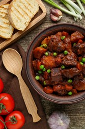 Photo of Delicious beef stew and ingredients on wooden table, flat lay