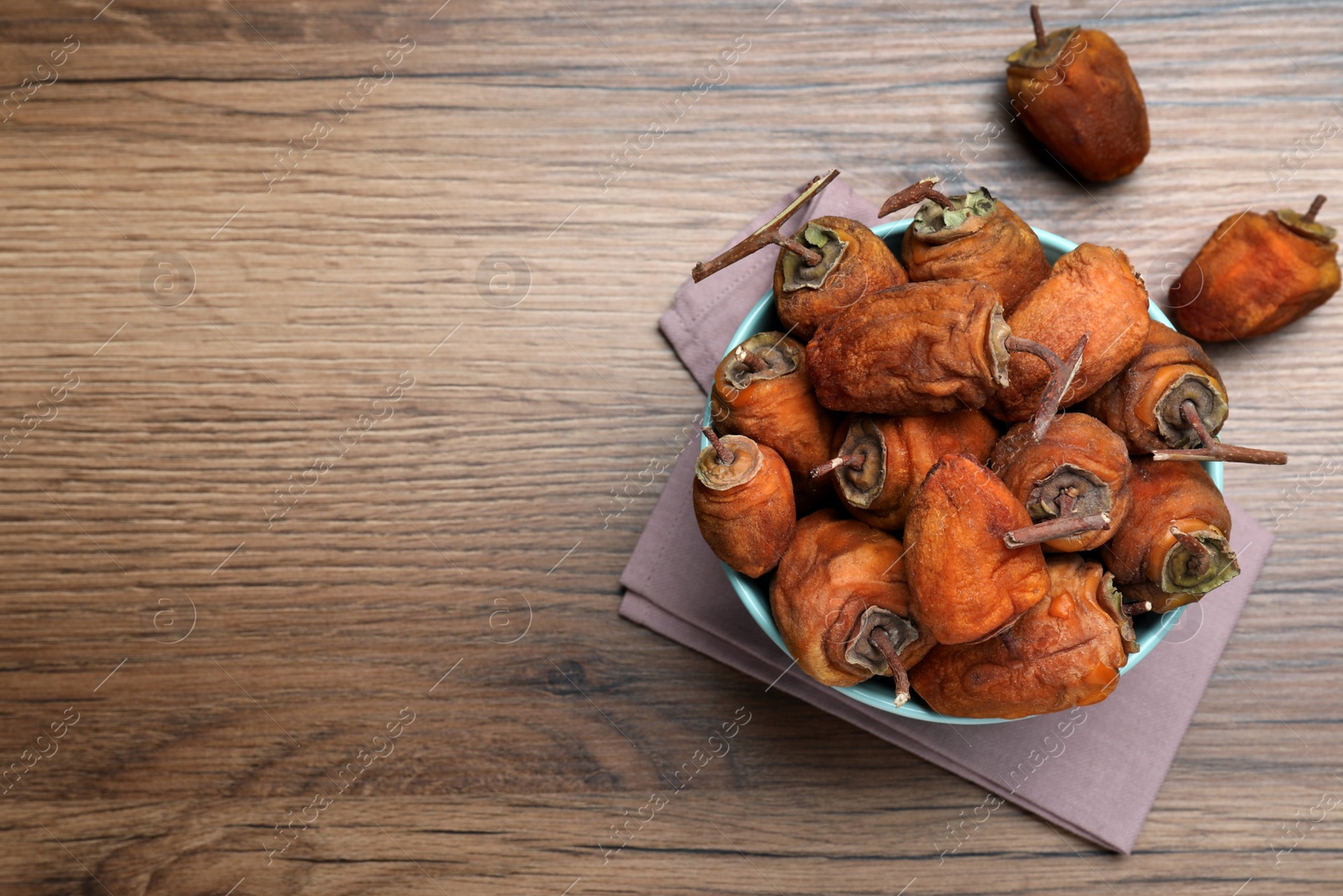 Photo of Bowl with tasty dried persimmon fruits on wooden table, flat lay. Space for text