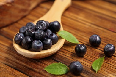 Photo of Ripe bilberries and leaves on wooden table, closeup