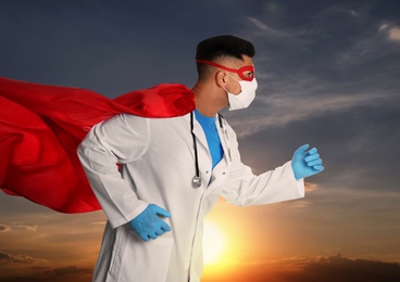 Image of Medical workers fighting with dangerous diseases. Doctor dressed as superhero posing against sky