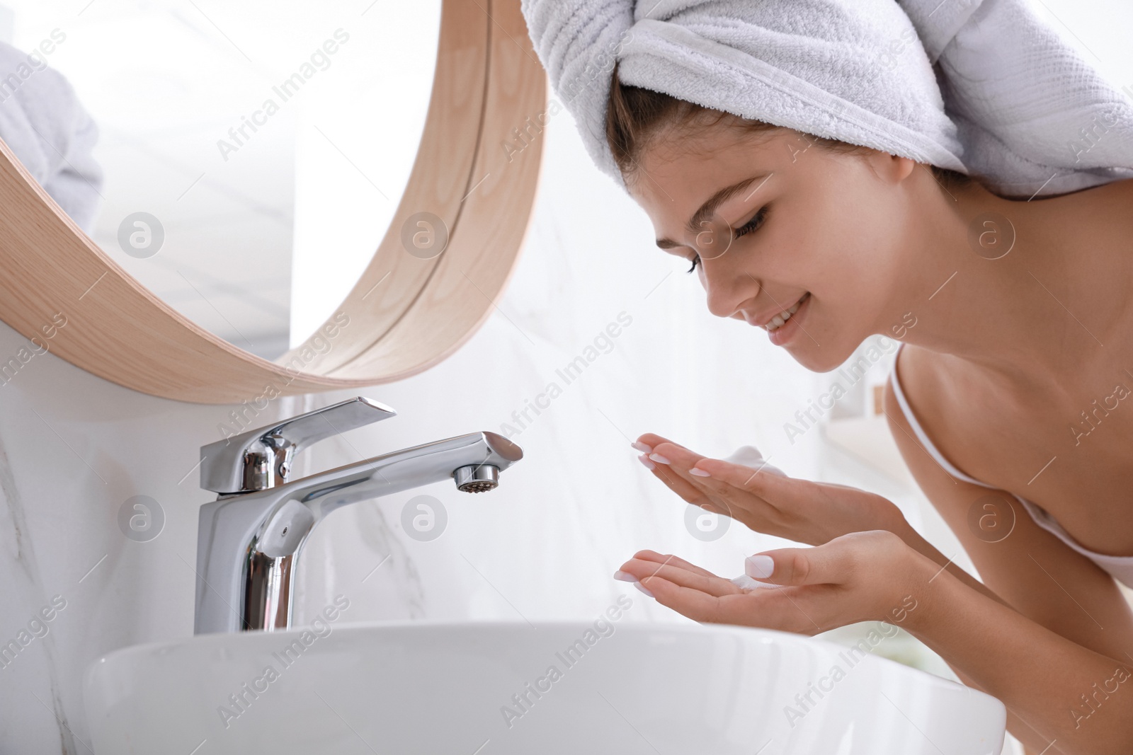 Photo of Beautiful teenage girl washing face with cleansing foam in bathroom. Skin care cosmetic