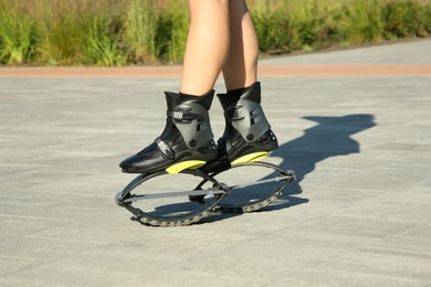 Photo of Woman in kangoo jumping boots outdoors on sunny day, closeup
