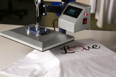 Photo of Printing logo. Heat press with t-shirt on white table, closeup