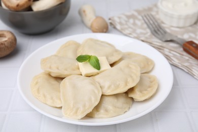 Delicious dumplings (varenyky) with tasty filling and butter on white tiled table, closeup