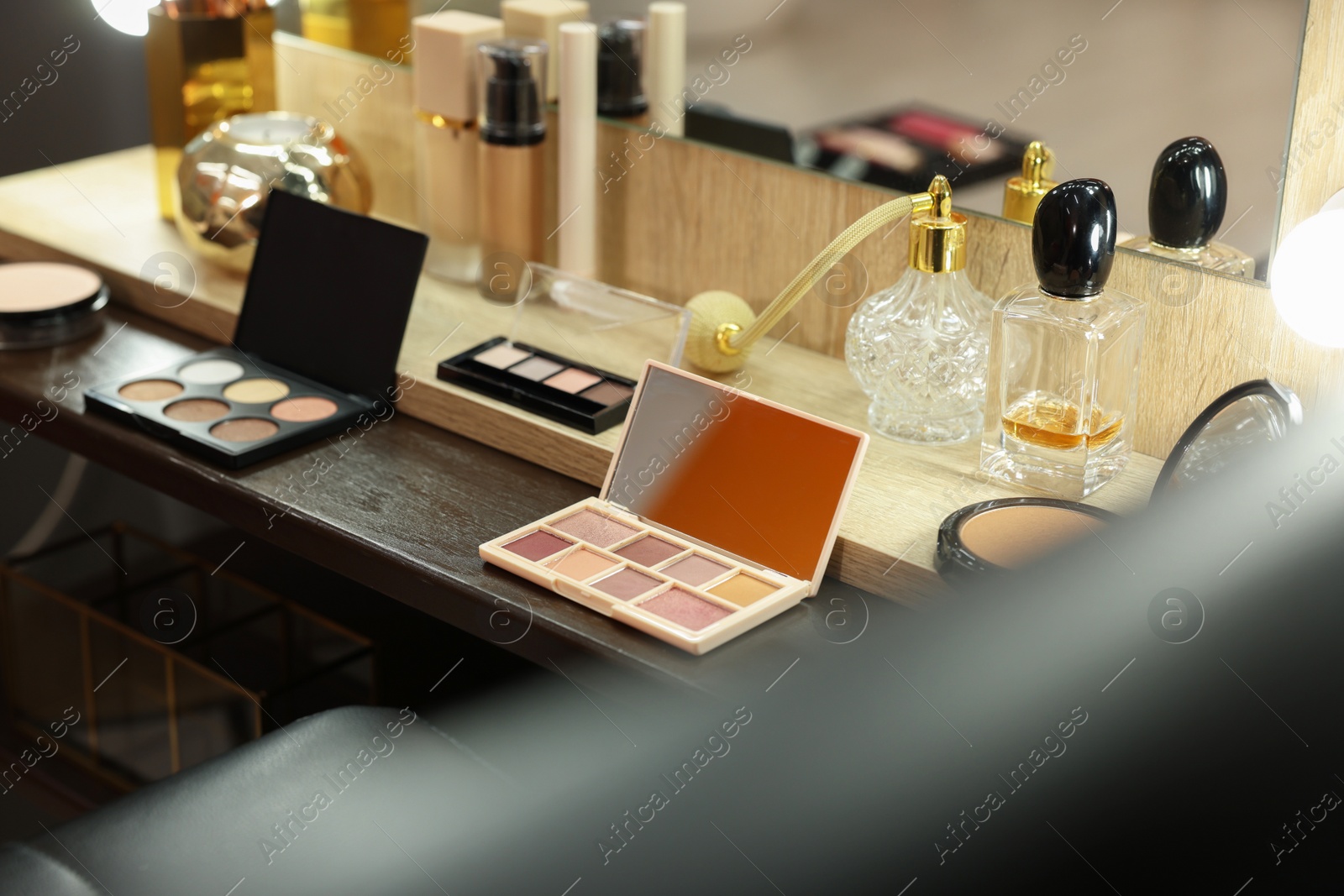 Photo of Makeup room. Cosmetic products and perfumes on wooden dressing table indoors