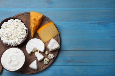 Photo of Clay dishware with fresh dairy products on blue wooden table, top view. Space for text