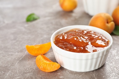 Photo of Bowl with tasty apricot jam on table