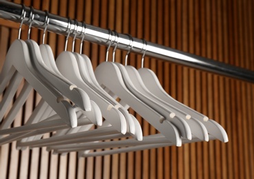 Empty hangers on rail against wooden background