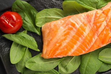Photo of Tasty grilled salmon with tomato and spinach on table, top view