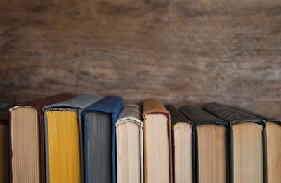 Stack of hardcover books on wooden background. Space for text