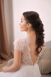 Photo of Beautiful young bride with wedding hairstyle indoors