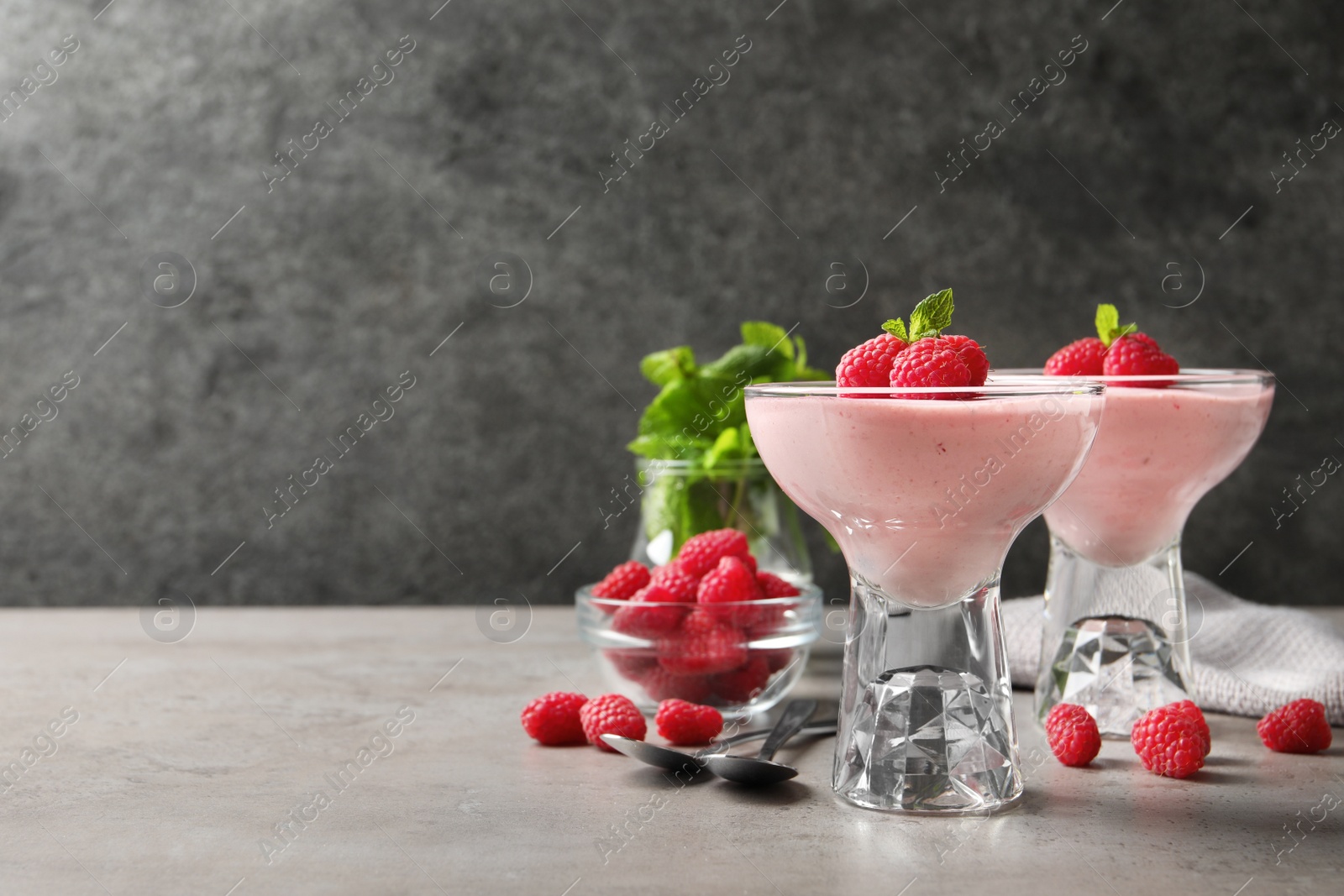 Photo of Delicious raspberry mousse with mint on light grey table, space for text