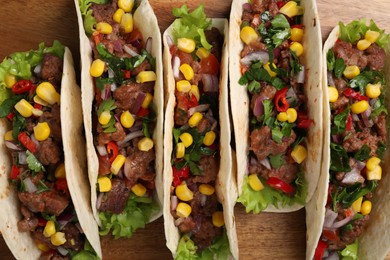 Photo of Delicious tacos with meat and vegetables on wooden table, top view